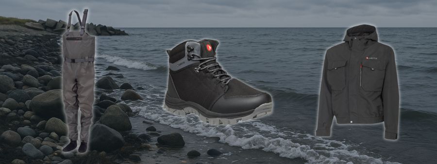 Greys Drypoint waders-s�t til skarp pris  waders, vadest�vler og jakke vist foran stenet kystlandskab.